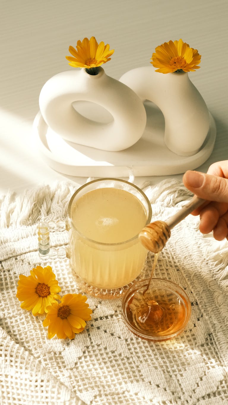Warm sunlight bathes a refreshing tea and honey setup with vibrant flowers.